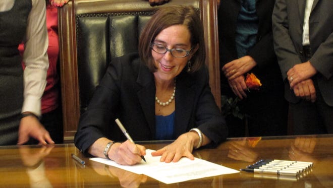 Gov. Kate Brown signs a bill expanding access to contraception during a ceremony at the state Capitol in Salem, Ore., on Thursday, June 11, 2015. The bill makes Oregon the first state to require insurers to pay for up to 12 months of birth control at a time. (AP Photo/Jonathan J. Cooper)                                 