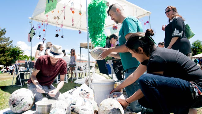 Dylan Schultz, left, Jose Arenivar and Taylor Reed of the History of Craft class make recycled piñatas for the community at the Craft Culture booth during the Earth Day celebration at New Mexico State University  on Sunday.