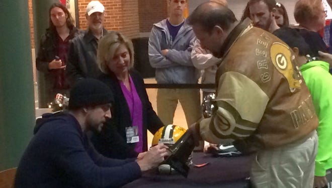 Green Bay Packers quarterback Aaron Rodgers, left, signs helmets and other items for fans in the Lambeau Field Atrium in Green Bay on Monday night, Dec. 12, 2016. Rodgers signed 200 autographs for a minimum donation of $100 each to raise money for The Salvation Army of Greater Green Bay.