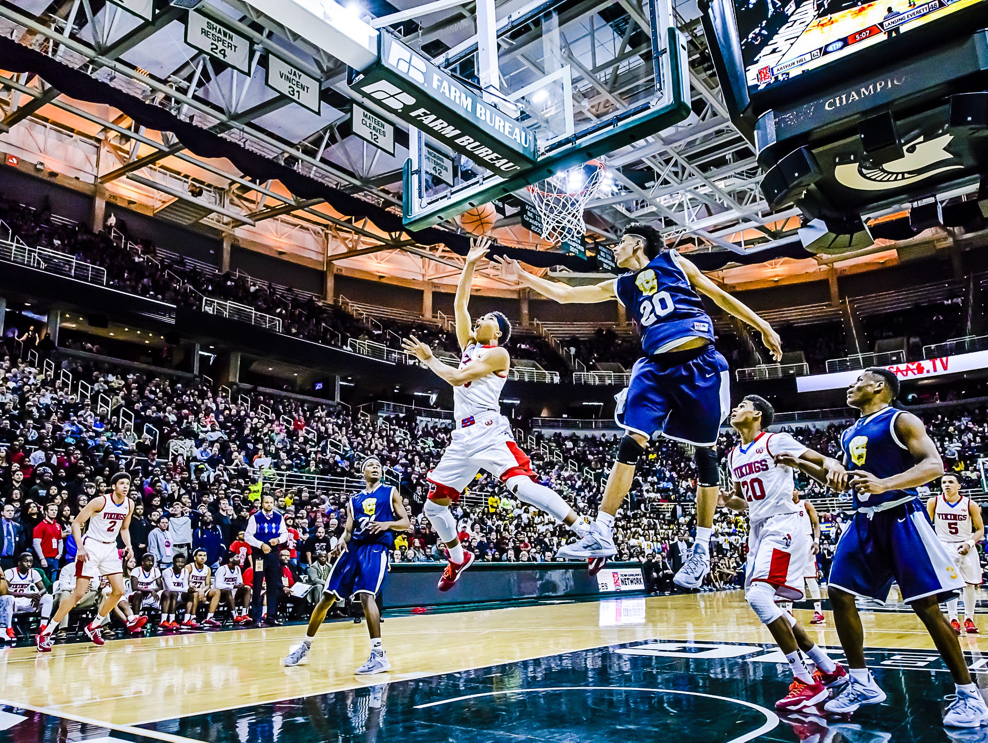 Everett's Deshae Doll lays the ball in past Saginaw Arthur Hill's Brian Bowen during a Class A state semifinal game in 2015 at Breslin Center.