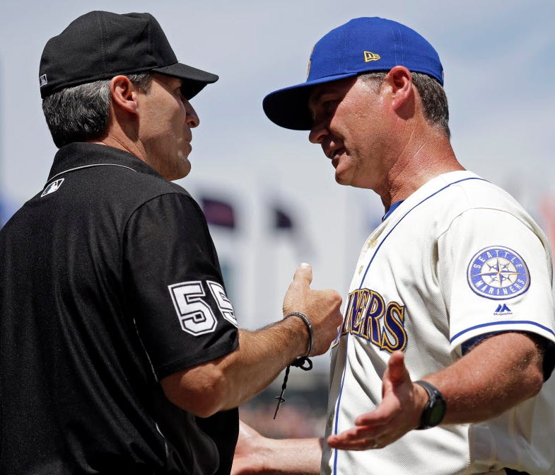 Seattle Mariners manager Scott Servais (right) talks with umpire Angel Hernandez after a call at home.