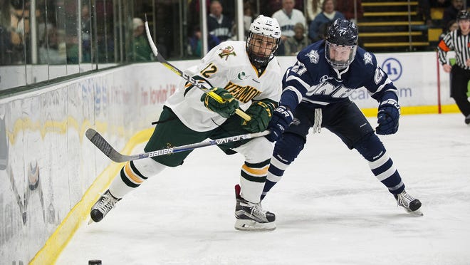Catatmounts forward Drew Best (12) and Wildcats defenseman Matt Dawson (27) battle for the puck during the men's hockey game between the New Hampshire Wildcats and the Vermont Catamounts at Gutterson Fieldhouse on Friday night February 10, 2017 in Burlington.