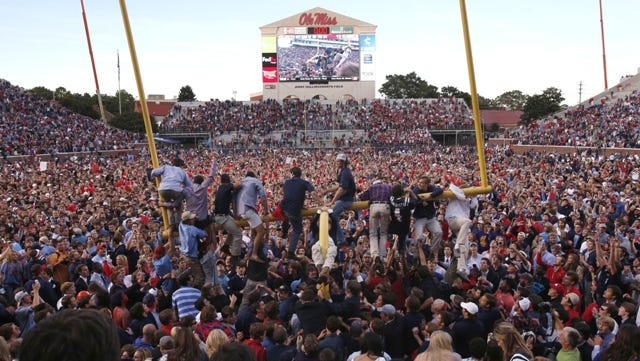 Mississippi fans gather on the field, while a few climb onto a goal post, after Mississippi defeated Alabama 23-17 in an NCAA college football game in Oxford, Miss., on Saturday Oct. 4, 2014. (AP Photo/Tuscaloosa News, Robert Sutton)