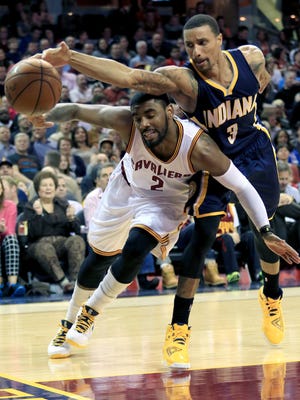 Indiana Pacers George Hill (3) reaches over Cleveland Cavaliers Kyrie Irving for a loose ball in the second quarter during a NBA basketball game Friday March 20, 2015 in Cleveland. (AP Photo/Aaron Josefczyk)