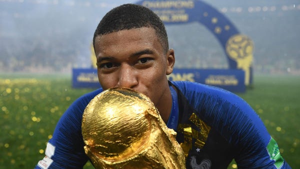 Kylian Mbappe kisses the World Cup trophy after...