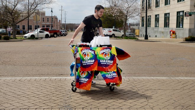 Woodstock Bakeshop manager Gene Gant crosses Liberty Street with his cart of sack lunches from the restaurant. Gant, who has a route that he walks, sells the sack lunches to employees of local downtown businesses.