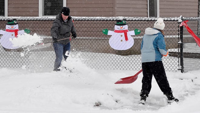 Amber Voegeli, left, and her daughter, Kiara, 16, help an elderly neighbor clear the sidewalks in front of his home near downtown St. Cloud after the overnight snowfall. The area received more than two inches of new snow by Saturday morning, Dec. 26.