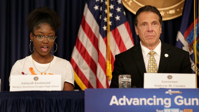 New York Gov. Andrew Cuomo listens as Aalayah Eastmond, a student at Marjory Stoneman Douglas High School, in Parkland, Fla., and survivor of the mass shooting there, speaks during a news conference in New York, Tuesday, June 5, 2018. Cuomo was announcing new gun control legislation that would aim to prevent mass shootings at schools.