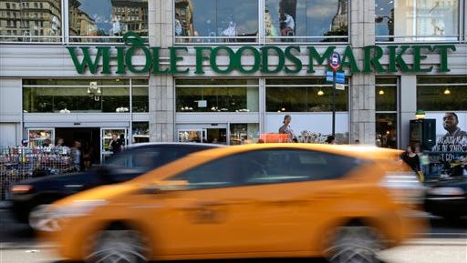 Pedestrians and motorists pass in front of a Whole Foods Market store in Union Square, Wednesday, June 24, 2015, in New York. New York City's consumer chief said Wednesday that Whole Foods supermarkets have been routinely overcharging customers by overstating the weight of prepackaged meat, dairy and baked goods. (AP Photo/Julie Jacobson) 