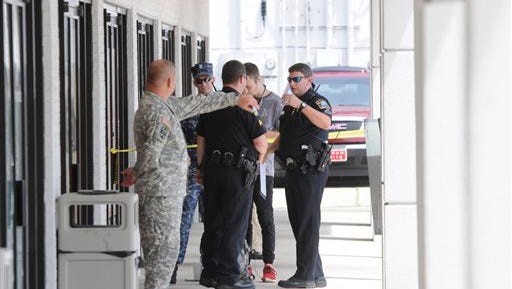 Chattanooga police talk to Reserve Recruitment Center personnel at the Lee Hwy office as the area is cordoned off with blue shell casing markers in the parking lot on Thursday, July 16, 2015 in Chattanooga, Tenn.  At least two military facilities in Tennessee were attacked in shootings Thursday, including one at a Navy recruiting building, officials said.    (Tim Barber/Chattanooga Times Free Press via AP) THE DAILY CITIZEN OUT; NOOGA.COM OUT; CLEVELAND DAILY BANNER OUT; LOCAL INTERNET OUT; MANDATORY CREDIT    