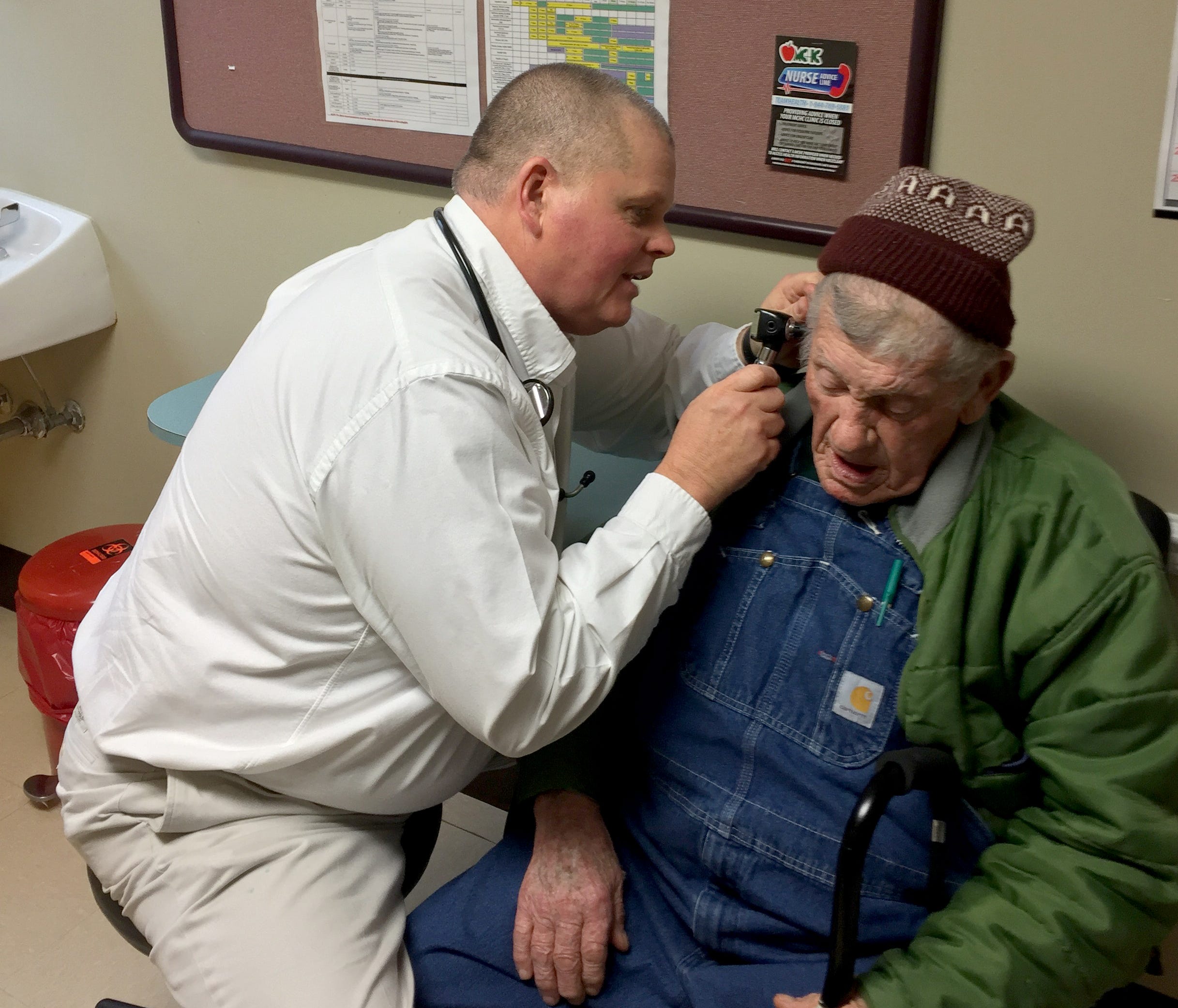 Van Breeding, a primary care doctor who is director of clinical affairs for Mountain Comprehensive Health in Kentucky, checks the ears of Lee Sexton, 88. Sexton is a nationally-known banjo player who has had Black Lung Disease since he was 65.