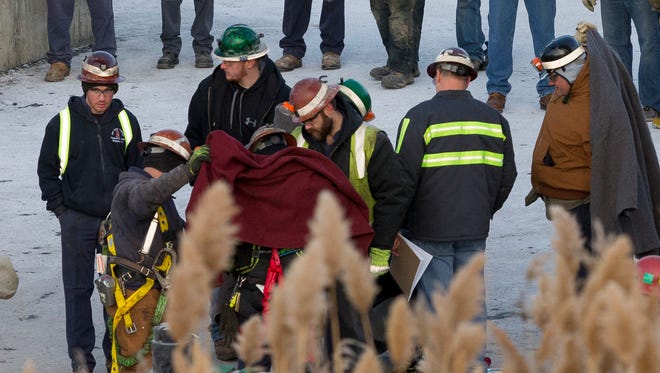 Miners from the second-last group to be removed from a stuck elevator at the Cargill salt mine in Lansing are given blankets after spending the night trapped in an elevator 900 feet below the surface.