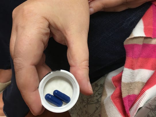 Kimberlie Newton holds two of the pills she's about