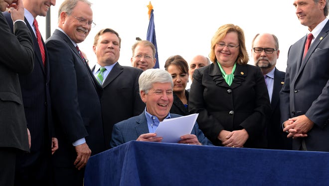 Michigan Governor Rick Snyder laughs as he signs the $1.2 billion road funding bill Tuesday, November 10, 2015 at the Michigan Infrastructure and Transportation Association in suburban Lansing. The plan passed the Legislature late on November 3.
