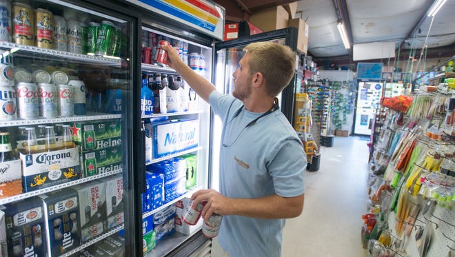 Gulf Breeze Bait and Tackle employee Alex Pilot stocks beer in a refrigerator at the store in Gulf Breeze earlier this month.