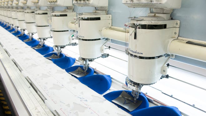 A line of embroidery machines at the New Era Cap Company places the Toronto Blue Jays logos on a shipment of caps.