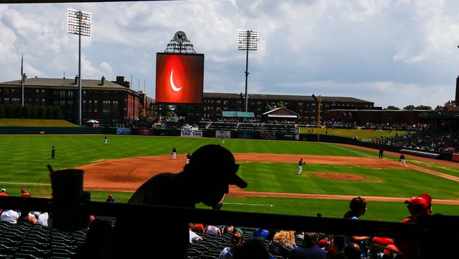 Fans take a moment to check on the eclipses on the scoreboard during a break in a action at the Memphis Redbirds Eclipse Party Monday afternoon.  