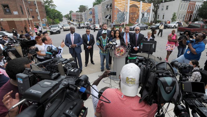 Baltimore State's Attorney Marilyn Mosby, at podium, holds a news conference near the site where Freddie Gray, depicted in mural in background, was arrested after her office dropped the remaining charges against three Baltimore police officers awaiting trial in Gray's death, in Baltimore, Wednesday, July 27, 2016. The decision by prosecutors comes after a judge had already acquitted three of the six officers charged in the case. At left is Gray's father, Richard Shipley. (AP Photo/Steve Ruark)