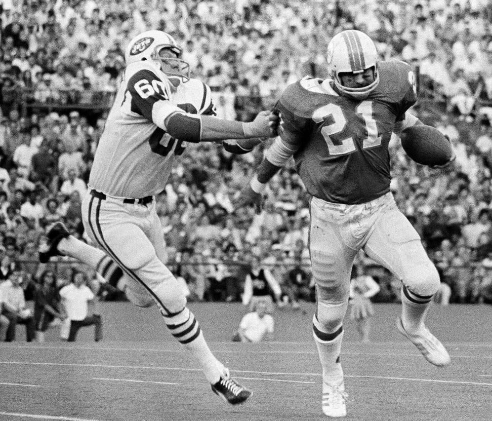Larry Grantham (60) catches Miami Dolphins back Jim Kiick by the sleeve to throw him for a one-yard loss on an attempted end run.