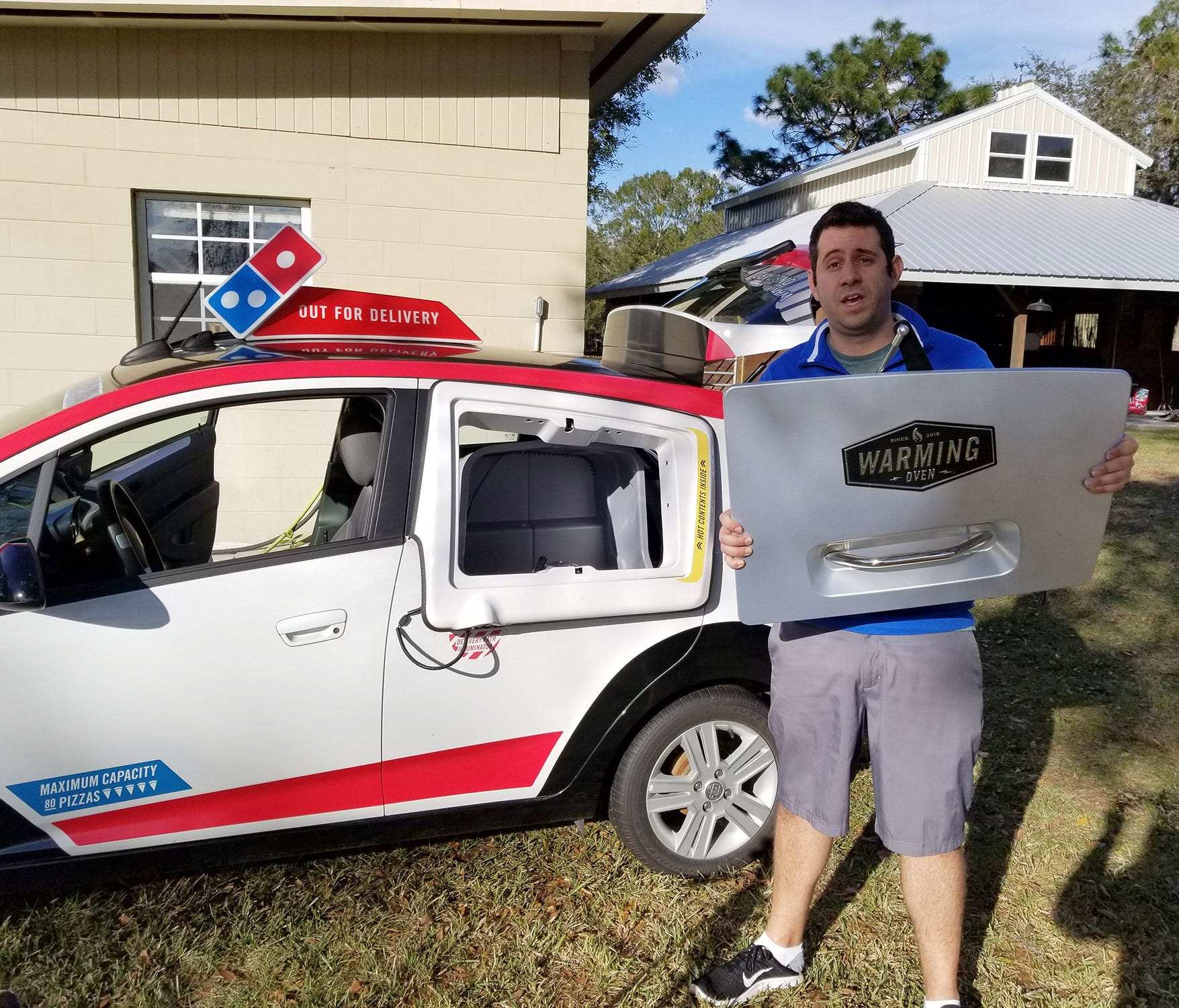 YouTube personality known as Samcrac is facing a potential legal threat from Domino's Pizza. He is with the Domino's Pizza delivery car he bought at auction and repaired.