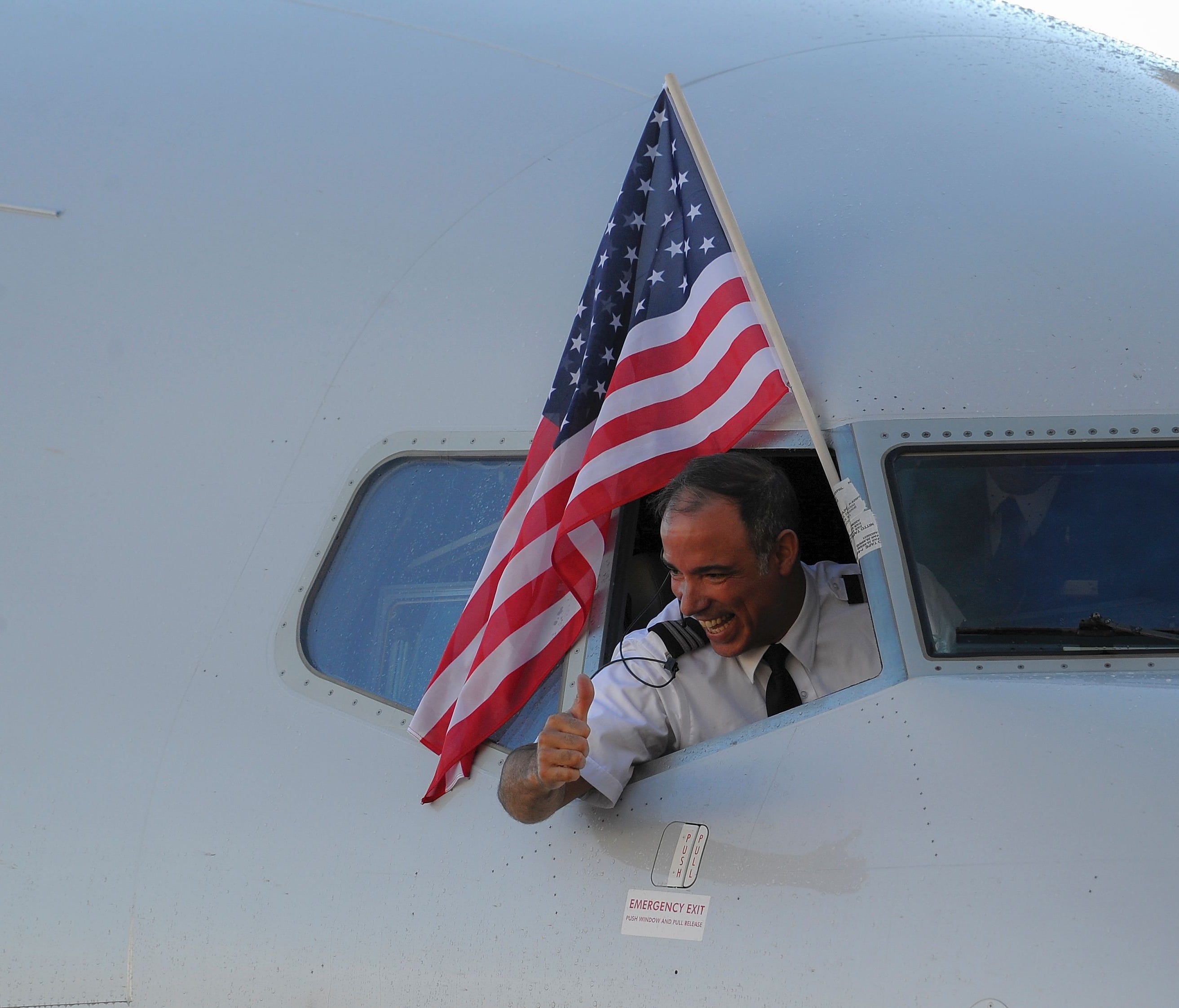 An American Airlines pilot gives a thumbs-up under the U.S. flag as the first regular flight from the USA to Havana arrives on Nov. 28, 2016.