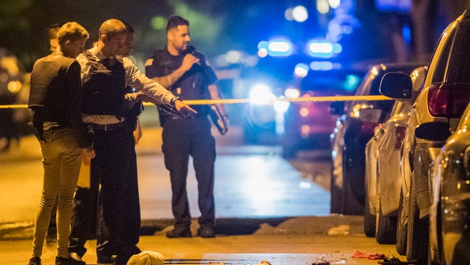 In this Thursday, June 14, 2018 photo, Chicago Police officers investigate the scene where two people were shot in Chicago.