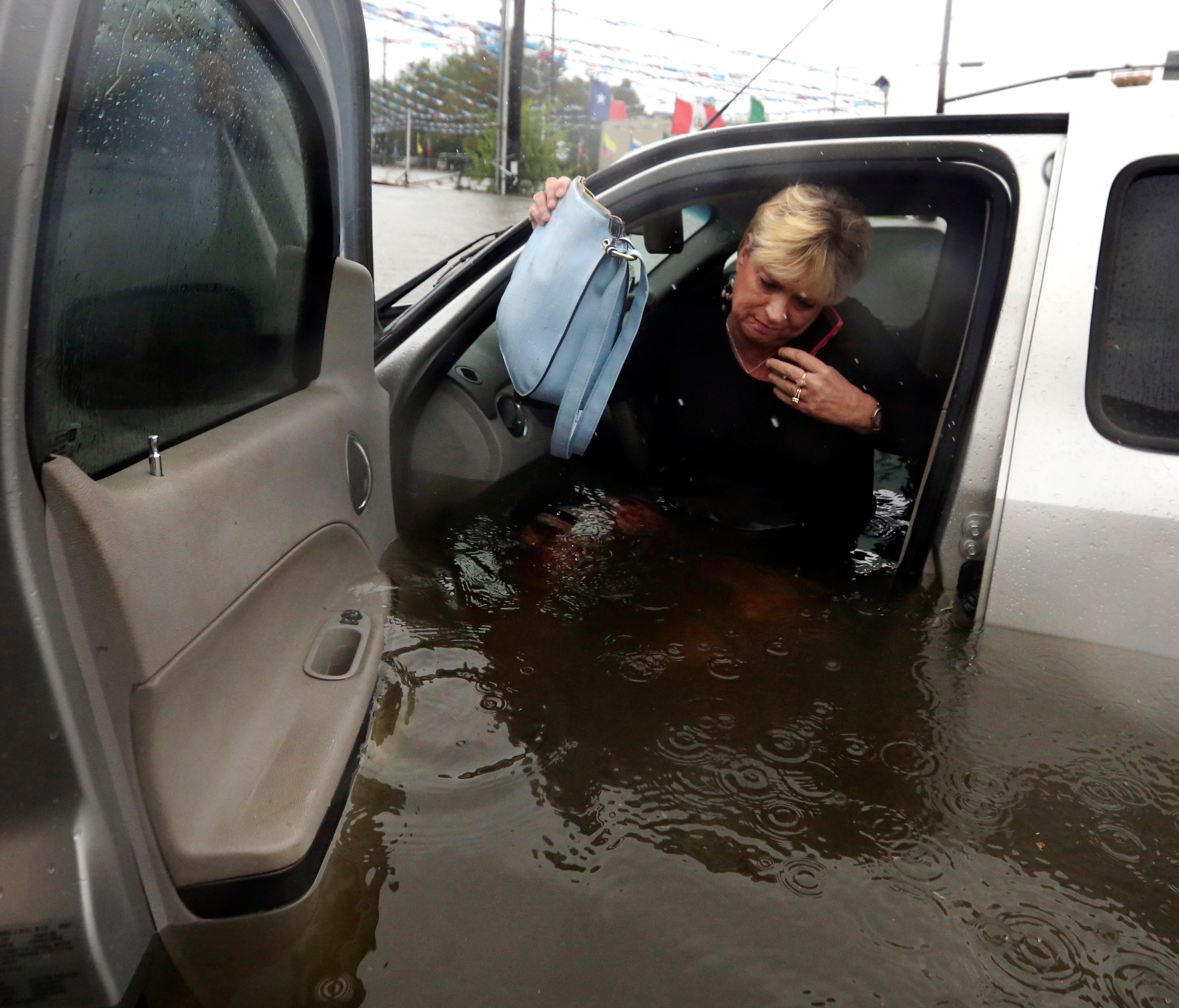 Rhonda Worthington talks on her cell phone with a 911 dispatcher as she gets out of her car after her vehicle become stalled in rising floodwaters from Harvey in Houston on Aug. 28.