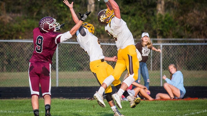 Monroe Central's Wyatt Snyder (2) and Israel Nash jump for an interception against Wes-Del during their game at Wes-Del High School Saturday Sept. 24, 2016. 