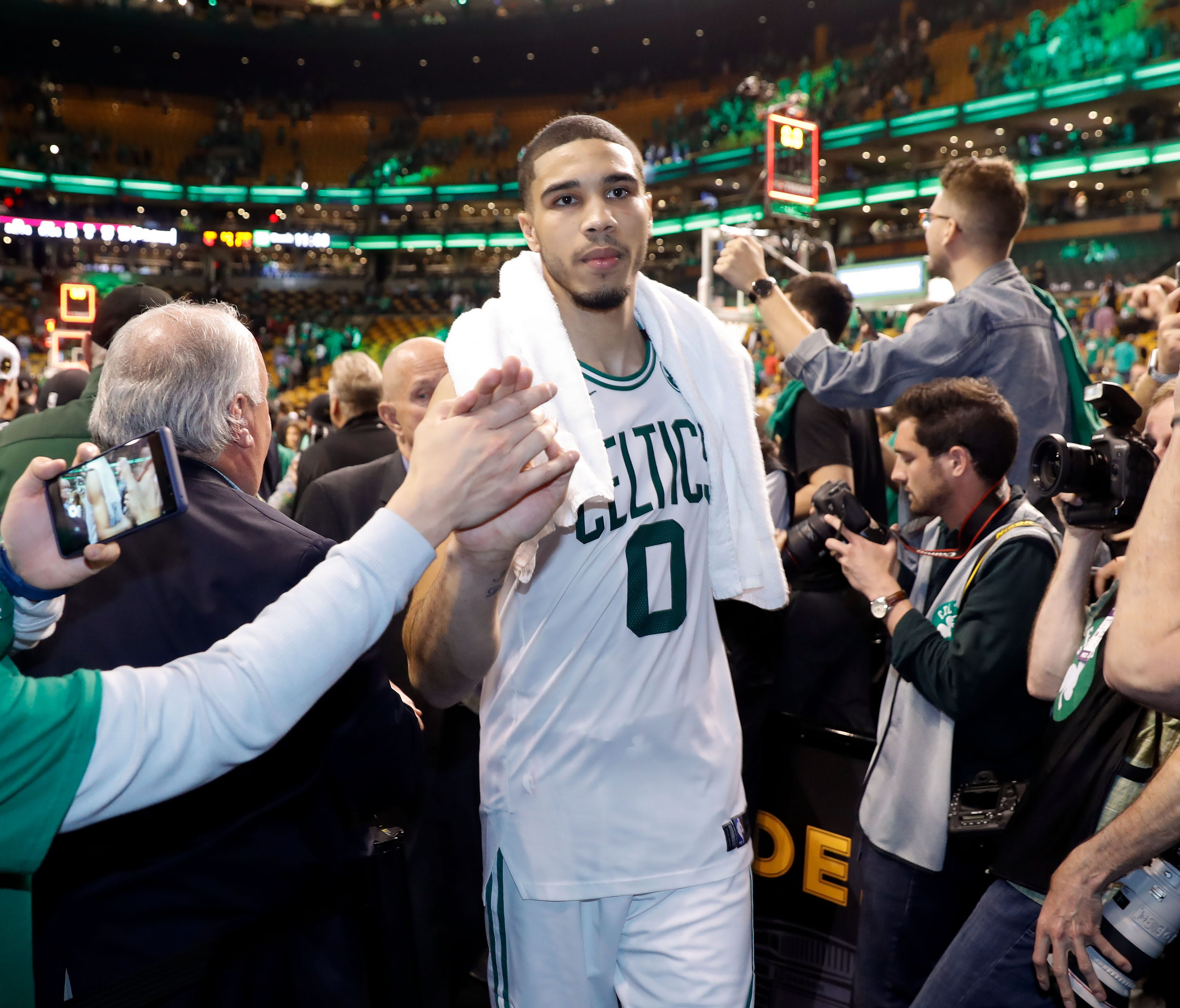 Boston Celtics forward Jayson Tatum (0) high-fives fans as he walks off of the court after defeating the Cleveland Cavaliers in game five of the Eastern conference finals of the 2018 NBA Playoffs at TD Garden.