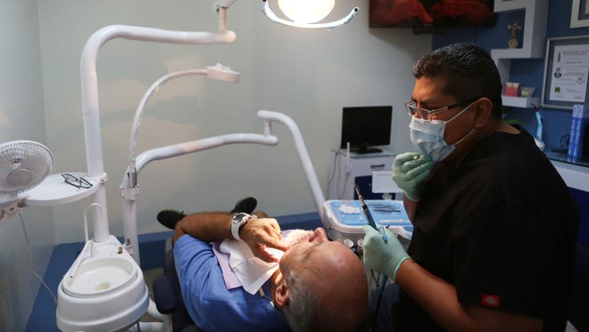 Palm Springs resident Vic Yepello describes some pain he has in a dental appointment with Dentist Marco Iiguez Raya on Wednesday, May 25, 2016 in Los Algodones, Mexico.