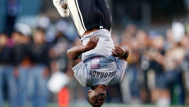 FILE - In this Oct. 15, 2016, file photo, Ozell Williams performs a somersault as part of pre-game ceremonies before Colorado hosts Arizona State in the first half of an NCAA college football game in Boulder, Colo. Williams, a coach who was shown on video pushing cheerleaders down in splits, was fired from another Colorado high school last year because of concerns about his techniques. Williams is among five school workers who were placed on leave from Denver East High School after the videos were made public and police opened an investigation. (AP Photo/David Zalubowski, file)