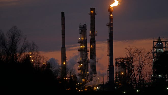 Stacks and burn-off from the Exxon Mobil refinery are seen at dusk in St. Bernard Parish, La., Friday, Feb. 13, 2015. (AP Photo/Gerald Herbert)