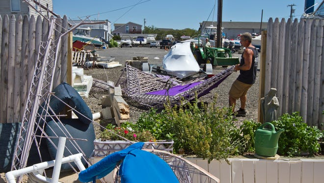 Rick Quelch of Duck Cove Marina cleans up a neighbors debris that broke through a fence and landed on the marina property. The marina lost 6 boats in the storm and the sign in front of their business along Long Beach Blvd. Residents and business owners clean up in Brant Beach after a storm tore through the area last night. Long Beach Township, NJWednesday, June 24, 2015@dhoodhood
