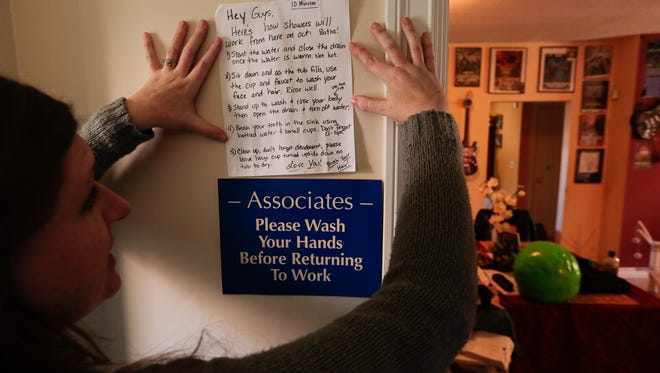 Melissa Mays of Flint shows a sign she has put in her bathroom for guests on the procedures in using Flint drinking water to bathe and clean with to limit exposure to the water that contains high levels of lead on Thursday October 1, 2015. 