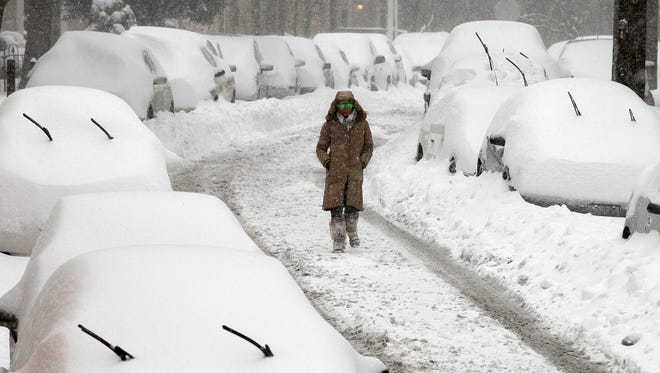A woman walks along a street in the East Falls section of Philadelphia on Saturday, Jan. 23, 2016. A blizzard with hurricane-force winds brought much of the East Coast to a standstill Saturday, dumping as much as 3 feet of snow, stranding tens of thousands of travelers. (Alejandro A. Alvarez/The Philadelphia Inquirer via AP)