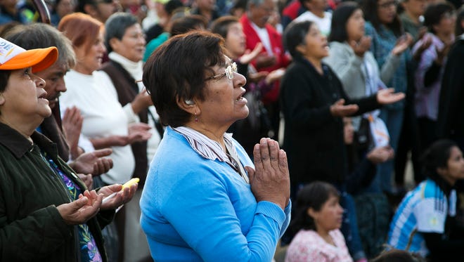 Maria Teresa of Mexico City, Mexico, prays with others as they watch Pope Francis celebrate Mass on a jumbo screen about a half mile away from the Basilica of Guadalupe where Pope Francis was celebrating the Mass in Mexico City, Mexico, on Saturday, Feb. 13, 2016.
