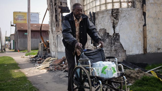 'I was drinking it I just said the heck with it,' Sam Ivory 73, said while walking along Saginaw St. in Flint's north side on Monday May 9, 2016 while carting his water in his wheel chair. 'I'm scared to drink and take baths in it.' Ivory picked up a case of water from the bus station during his daily commute that he carted before needing to readjust and push himself down the street with it on his lap.