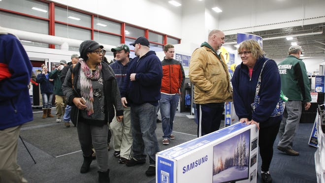 Black Friday shopper Monica Fox, of Okemos, scores a 48" television early November 27, 2015, as a line of early bargain-hunters continue to file into Best Buy in Okemos.