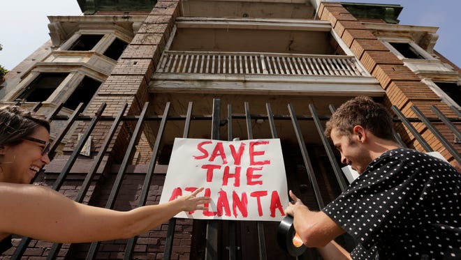 Miranda Day, left and Mark Hall, both of Detroit hang signs on the fence around the Atlanta building on Cass Avenue where people gathered to raise awareness about the value of preserving historic buildings and asked that a group of buildings including the Atlanta and Hotel Ansonia not be demolished in Detroit on Thursday, August 24, 2017.