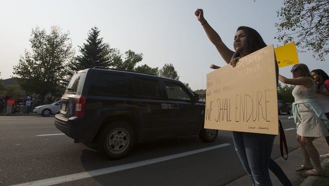 Colorado State University student Carla Lopez clenches her hand in a fist while holding her sign during the DACA Solidarity Rally on Tuesday in Fort Collins.
