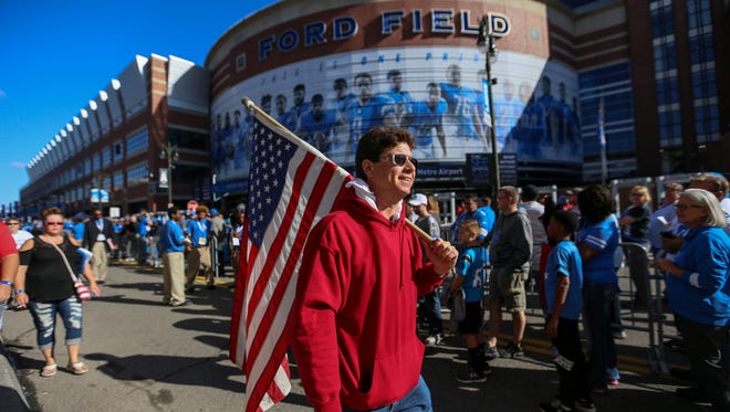 Kevin Grand, of Armada Twp, carries an American flag as he walks through the crowd in Pride Plaza outside of Ford Field in Detroit for the Detroit Lions game against Carolina Panthers on Sunday, Oct. 8, 2017. Grand is protesting NFL players taking a knee during the National Anthem. Although its a public street the protestors were told they could not protest in Pride Plaza because it is owned by the Detroit Lions.