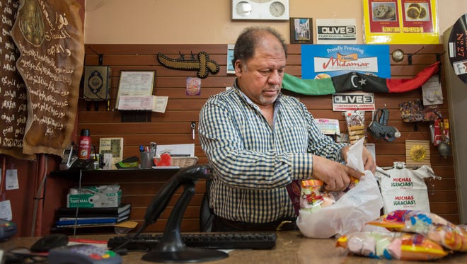 Shop owner Taher Misurati bags up a customer's groceries, Friday, Oct. 20, 2017, at the Olive Tree Market on South College Avenue in Fort Collins, Colo.