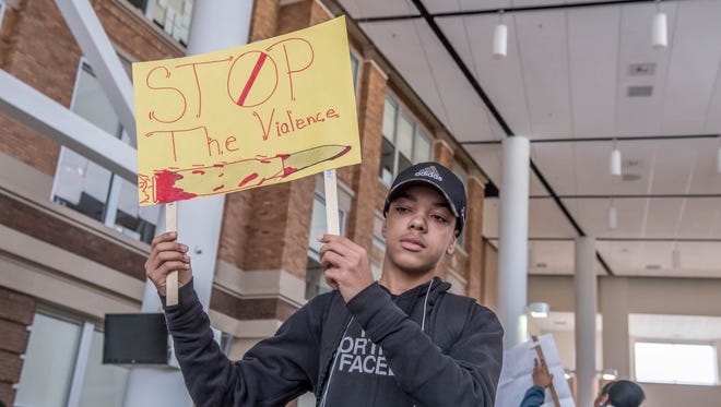 Battle Creek Central freshman Romello Thompson holds a sign during a rally at the school to honor the 17 students and teacher killed last month in a high school shooting in Florida.