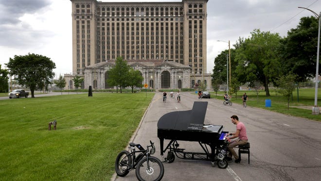 Davide Martello of Germany plays his piano in front of Michigan Central Station during a two day stop in Detroit in May 2015. Martello travels the world playing his piano in public spaces. Within a city he pulls it behind a bicycle and when it is time to move to the next town he loads it up in a trailer that he drives behind his 1991 VW Corrado.