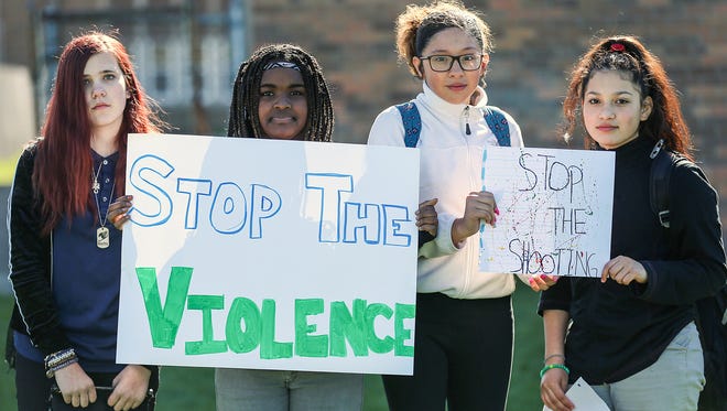 From left, Elizabeth Starker, 12, Precious Allen, 13, Viridiana Coria, 14, and Diana Peralta, 13, hold signs after walking out of Longfellow Middle School in Indianapolis on April 20, 2018, the 19th anniversary of the Columbine school shooting. Students had a moment of silence to remember the 13 victims of the shooting and held small group discussions about gun violence and school safety.