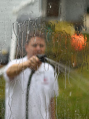 Michael Schwartz-Oscar, executive director with the Volunteer Center of Brown County, hoses down a window at a resident's home off East River Drive in Allouez on Saturday. A group of volunteers were taking part in this weekend's local and national Make A Difference Day.