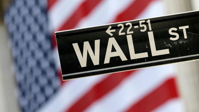 In this Tuesday, Sept. 8, 2015, file photo, a Wall Street street sign is framed by a giant American flag hanging on the facade of the New York Stock Exchange.