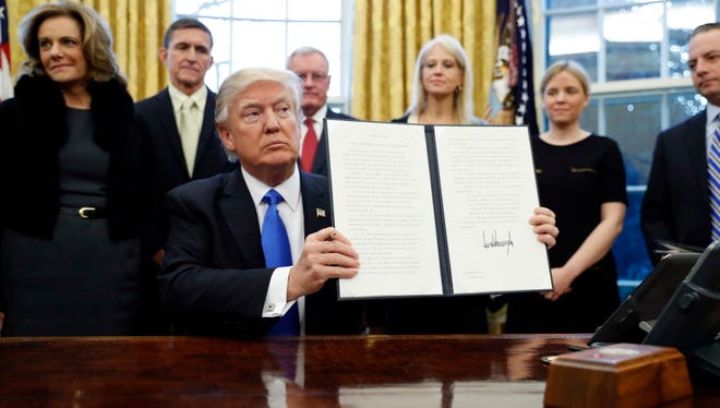 President Trump holds up a signed Executive Order in the Oval Office of the White House on Jan. 28, 2017.