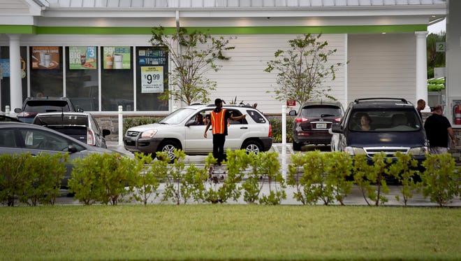 A parking attendant directs traffic Saturday, Sept. 9, 2017, at the gas pumps of the Cumberland Farms store at the intersection of Port St. Lucie and Darwin boulevards as a light rain saturates the area ahead of Hurricane Irma.