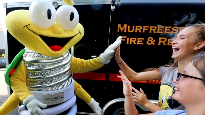 Brianna Dykes, 10, foreground, and Karrie Haslam, 14, give Louie the Lightning Bug a high-five during the National Night Out event on the square in Murfreesboro on Tuesday, Aug. 2, 2016.